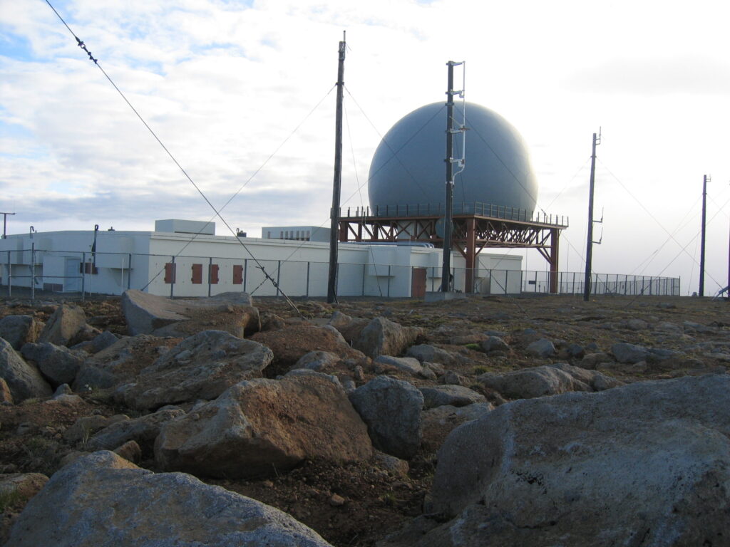 The mountain Bolafjall rising above the town of Bolungarvík in the Westfjords of Iceland, with the radar station visible near its summit.