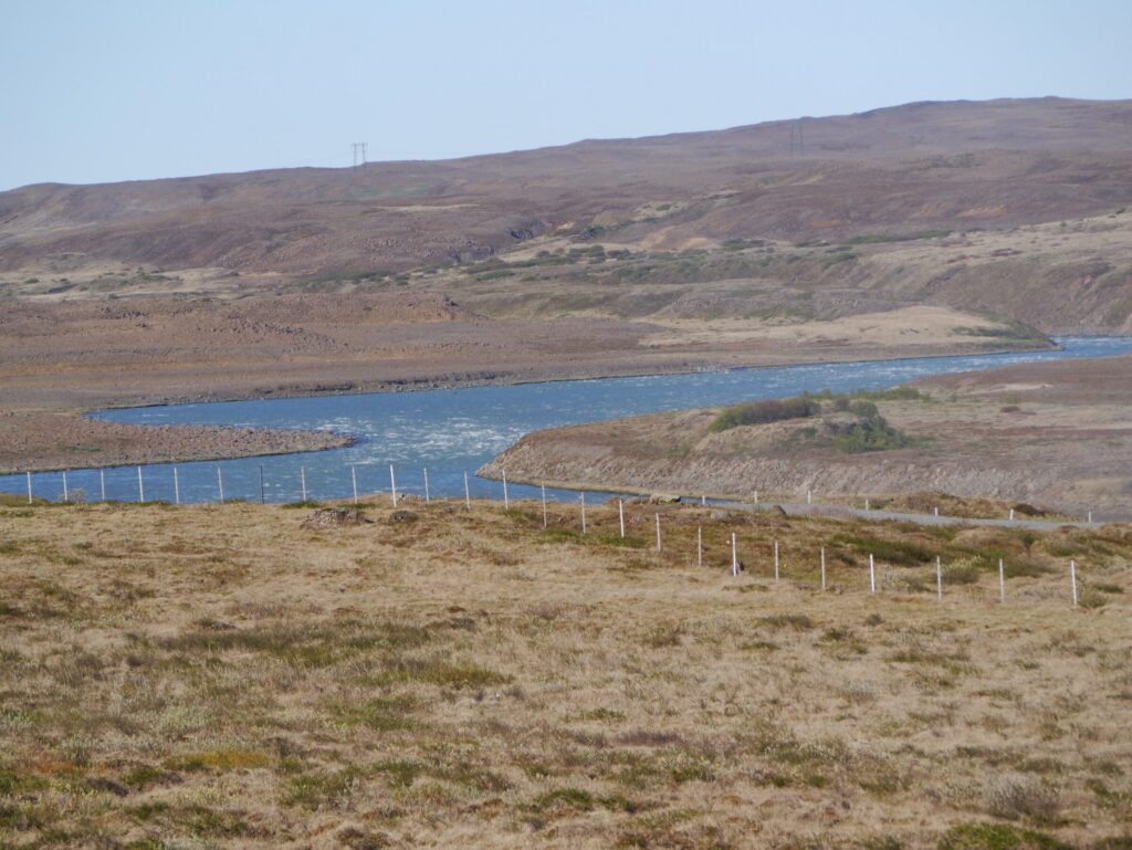 Wide view of the calm Hvítá river winding through the grassy valley of Borgarfjörður