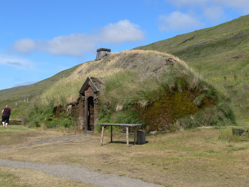 The reconstructed turf-and-timber Viking longhouse at Eiríksstaðir, seen from outside with grassed turf walls under an overcast sky.
