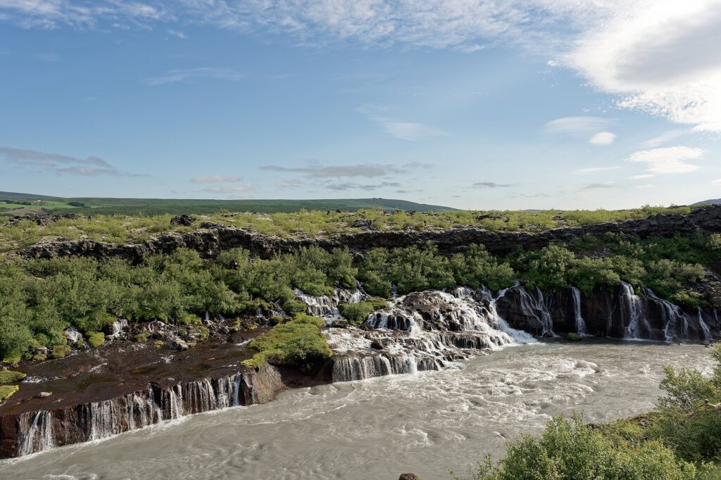Hraunfossar waterfalls streaming out of the lava field into the blue Hvítá river, West Iceland