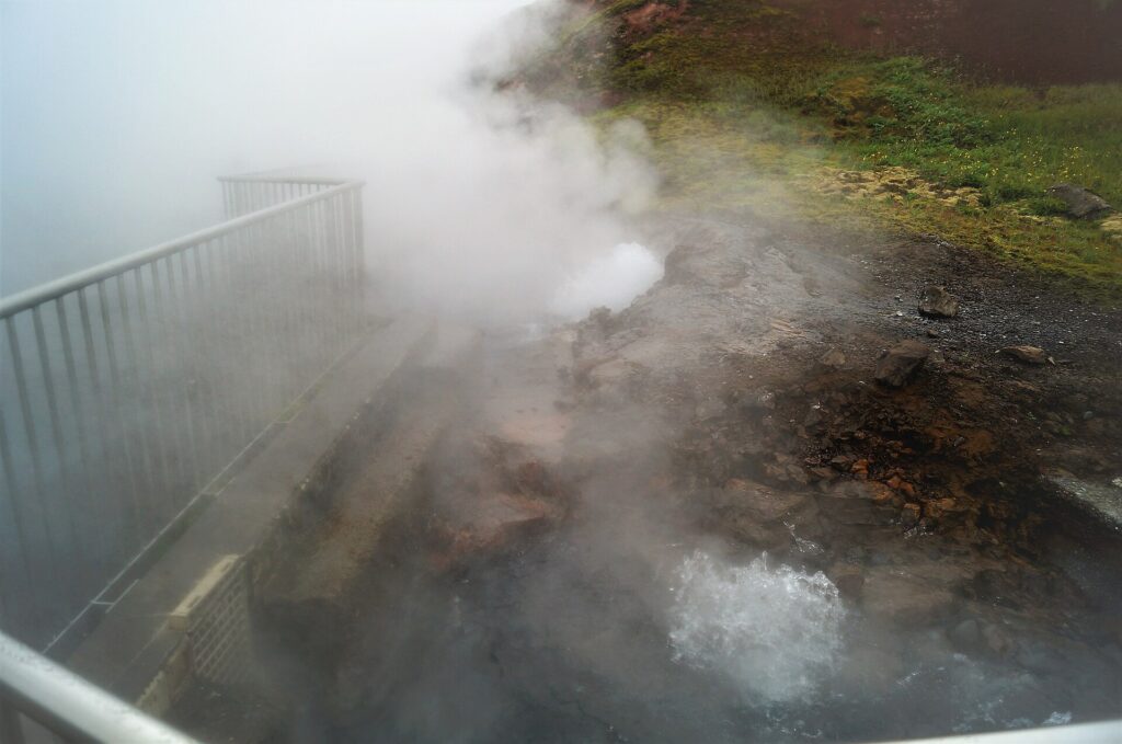 Boiling, steaming water surging up through mineral-crusted rock at the Deildartunguhver hot spring in West Iceland
