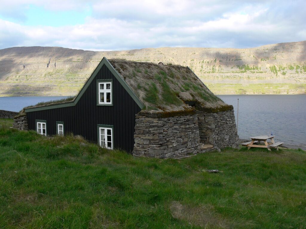 The turf-roofed farmhouse of Litlibær in Skötufjörður, Iceland, with its sod roof and stone-and-timber walls beside the fjord.