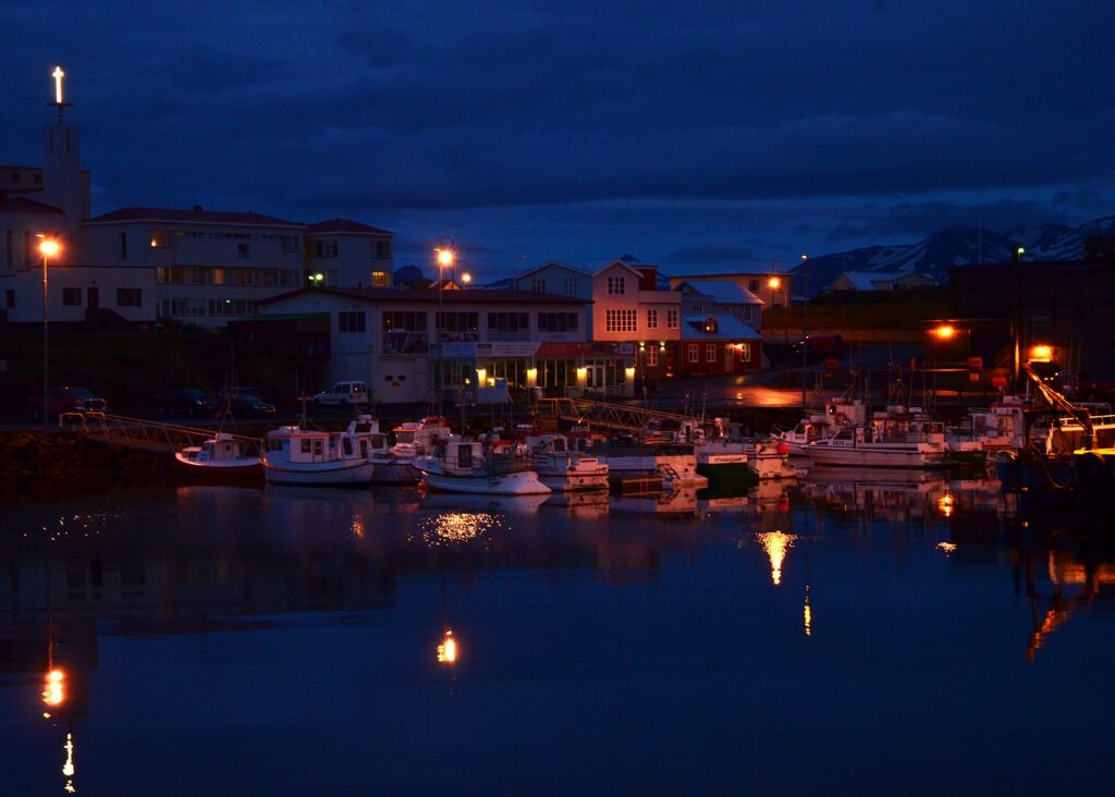 Stykkishólmur harbour glowing under the soft, low light of the midnight sun, with fishing boats moored along the quay.