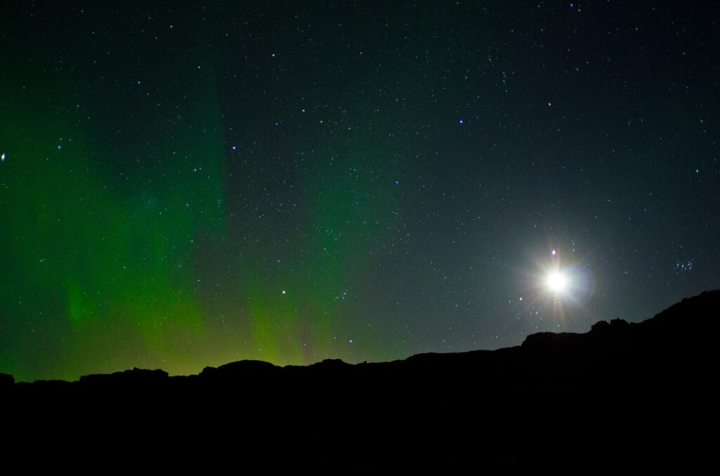 Green aurora borealis glowing over a dark Icelandic landscape at night