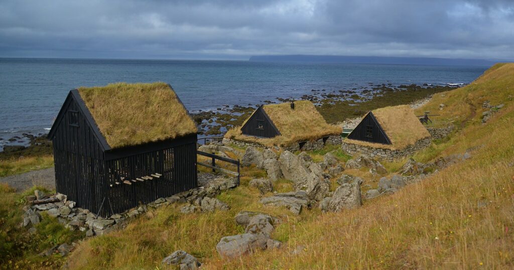 Turf-roofed stone buildings of Ósvör Maritime Museum on the shore near Bolungarvík, Iceland