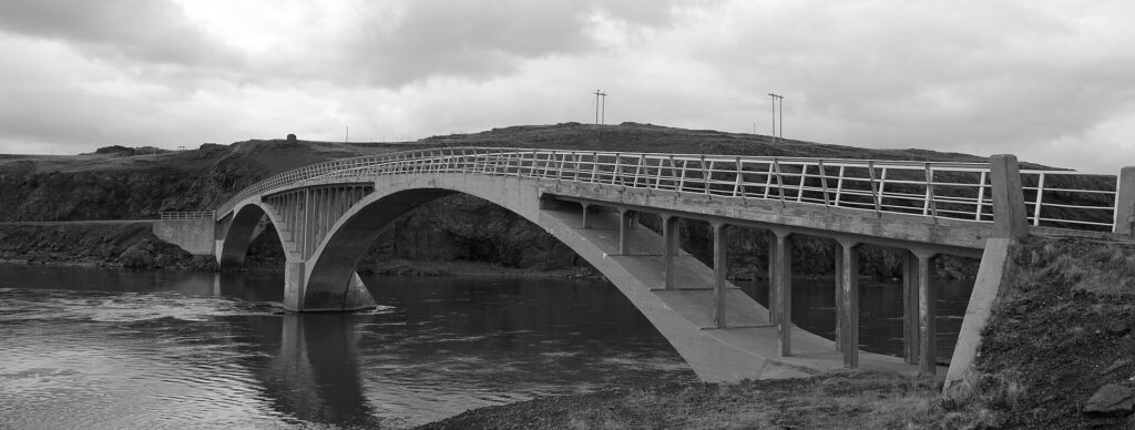 The old bridge over the Hvítá river in Borgarfjörður, West Iceland, spanning the wide glacial river under an open sky.