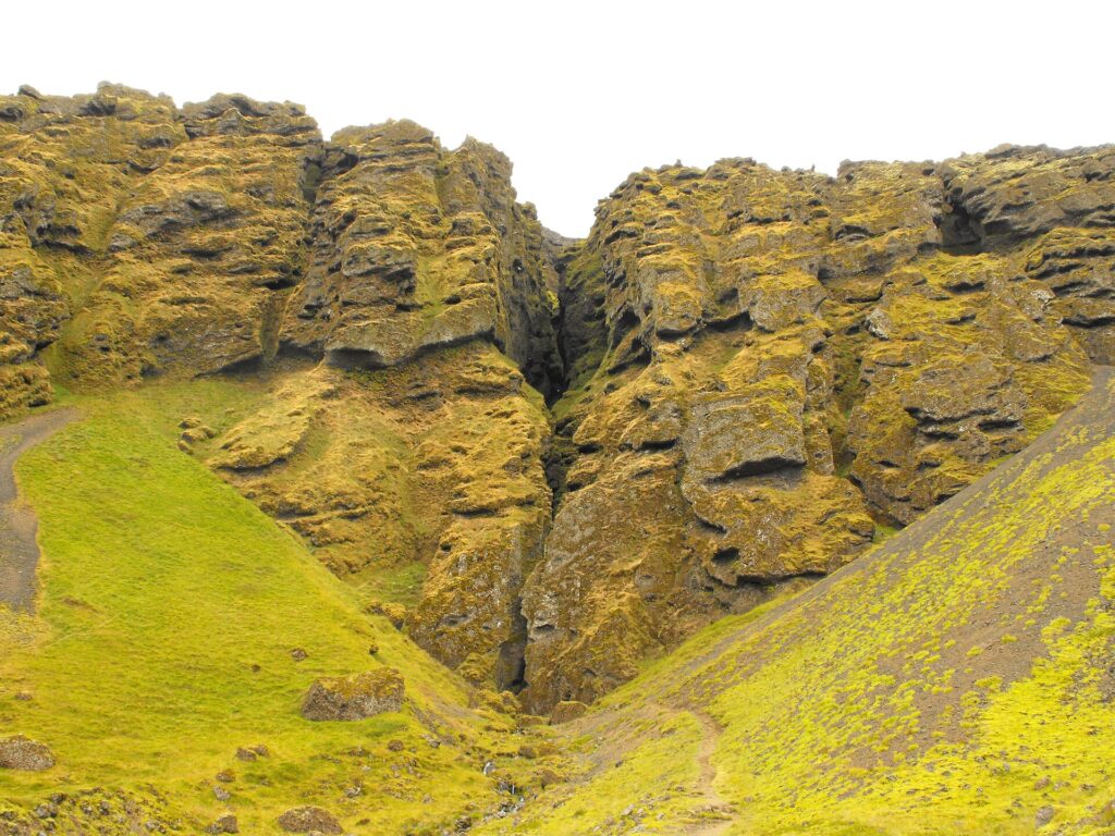 Narrow rocky gorge (Rauðfeldsgjá) cut into a mountainside on the Snæfellsnes Peninsula, Iceland, with a stream running through it