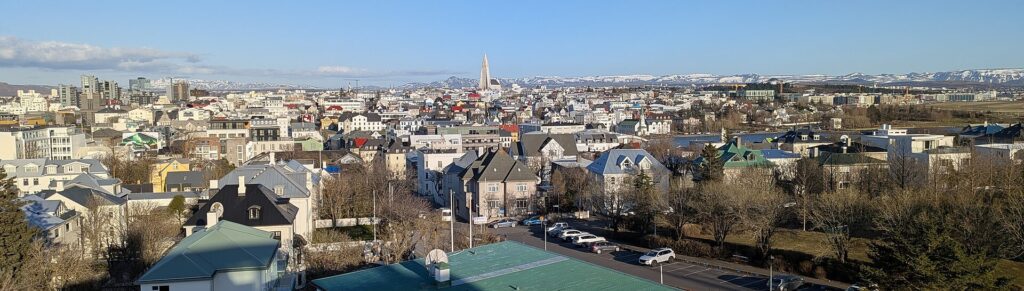 Panorama of central Reykjavík with coloured rooftops and the Hallgrímskirkja church tower rising above the city.