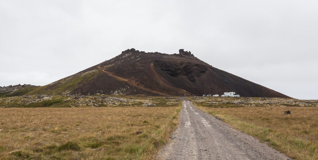 View from the rim of Saxhóll crater over the red scoria slope and the Neshraun lava field toward the coast in Snæfellsjökull National Park, Iceland