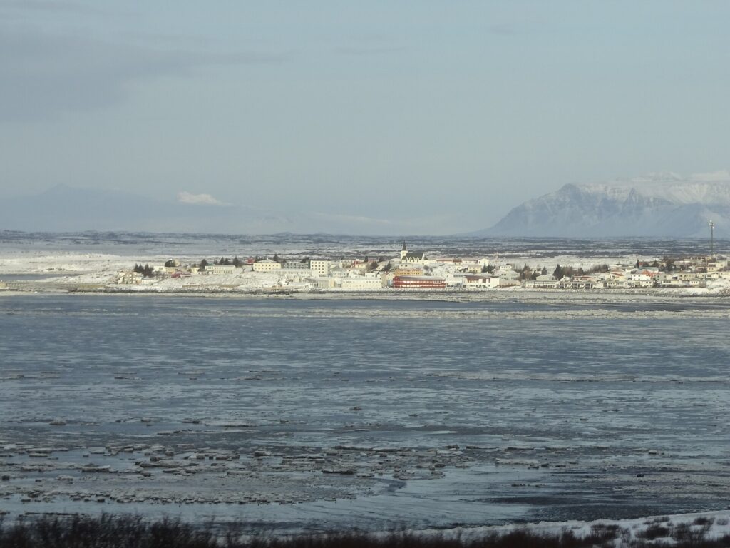 Coastal view of the town of Borgarnes, West Iceland, with buildings along the shore beside the water where the Settlement Center stands.