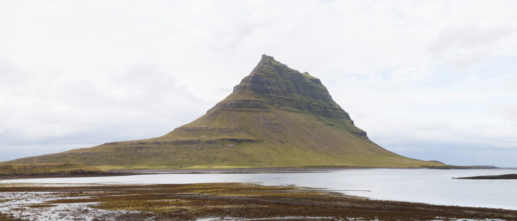 Kirkjufell mountain rising above the coast on the north side of the Snæfellsnes peninsula, West Iceland, with the small Kirkjufellsfoss waterfall in the foreground.