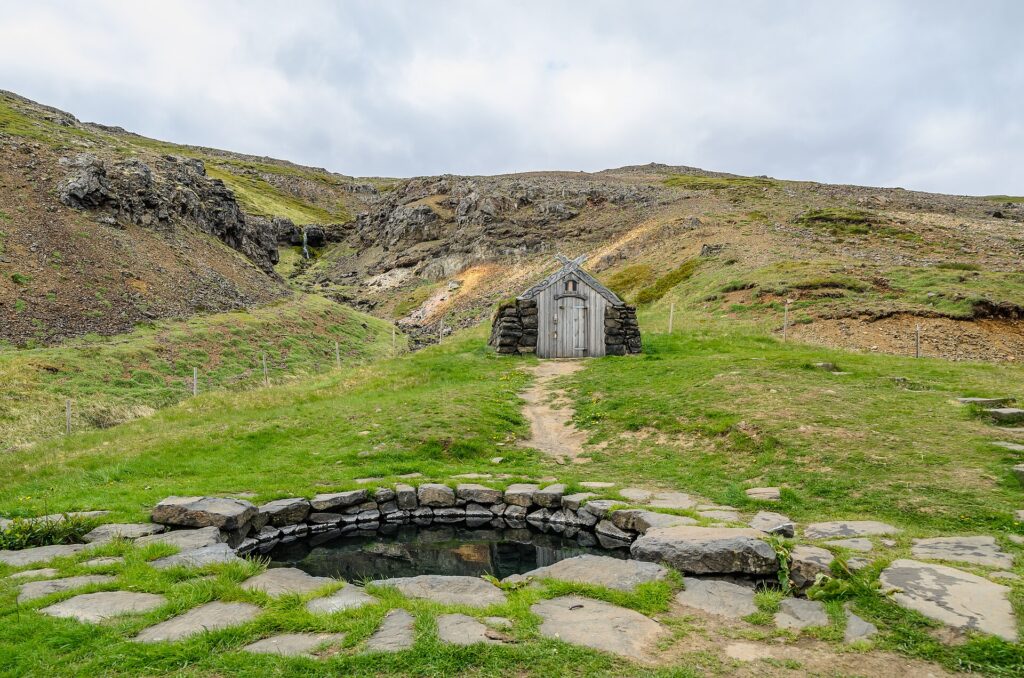 Guðrúnarlaug, a small turf-and-stone hot pool set into a grassy hillside near Laugar in Sælingsdalur, Dalabyggð, Iceland