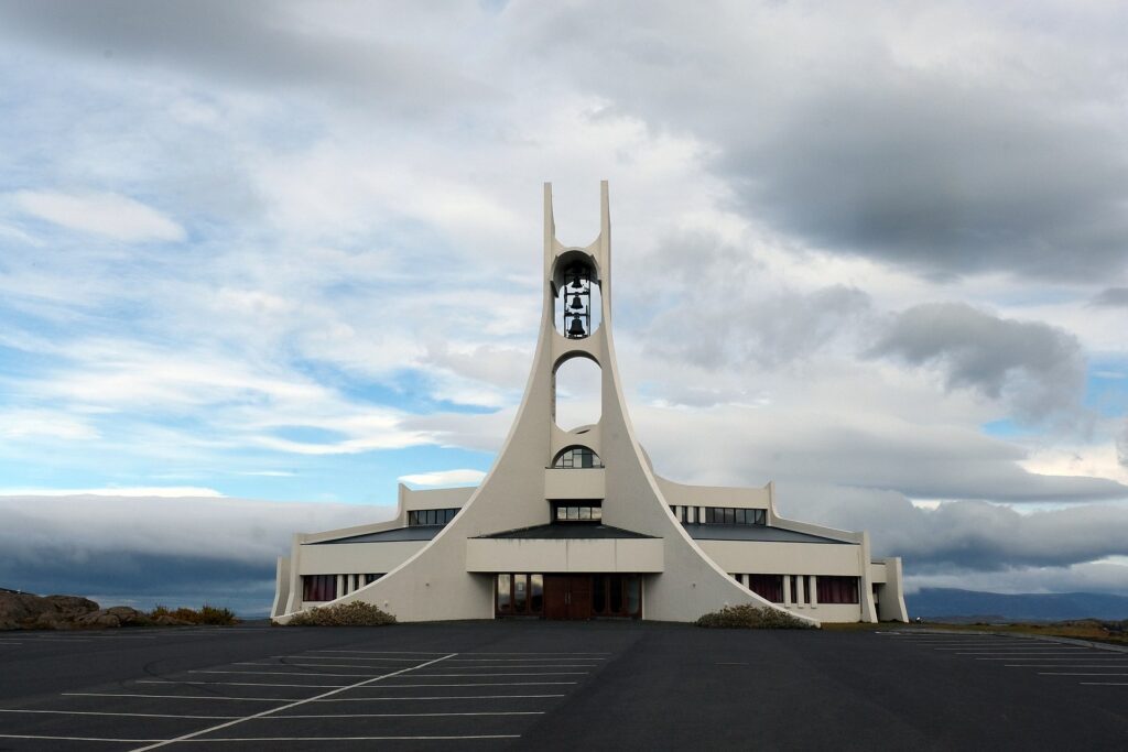 White modernist Stykkishólmskirkja church with curved concrete towers on a hilltop above Stykkishólmur, Iceland