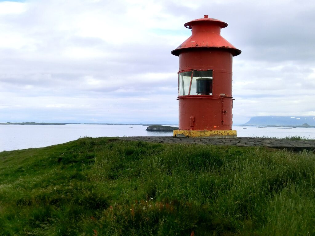 The small orange lighthouse atop the basalt cliffs of Súgandisey island overlooking Breiðafjörður near Stykkishólmur