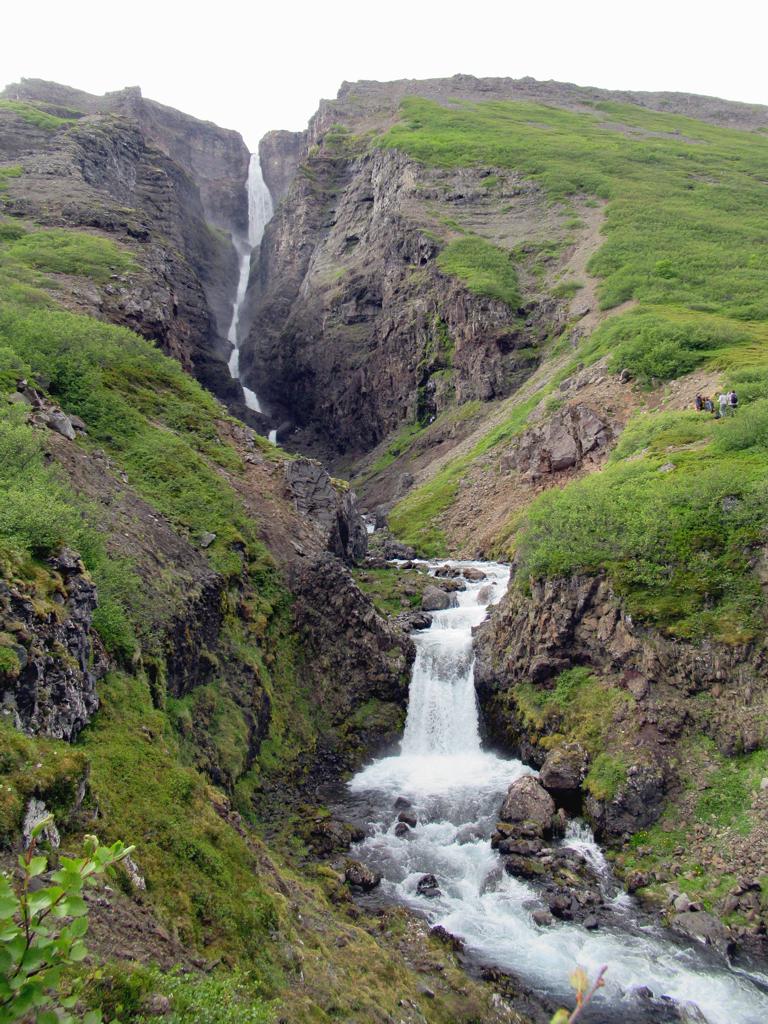 The Valagil waterfall dropping down a wall of layered ancient lava inside a narrow ravine at the head of Álftafjörður, Westfjords, Iceland.