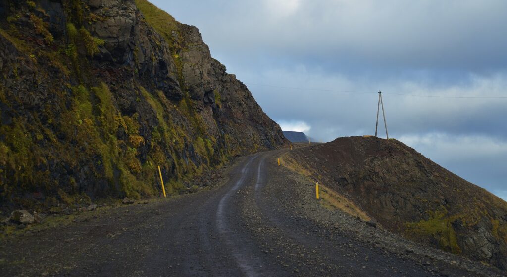 A gravel road winding through the fjords and mountains of the Westfjords, Iceland